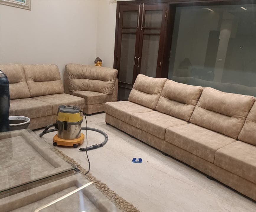 Beige sofa set being cleaned with a wet vacuum in a living room
